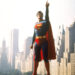 superman pointing to the sky with a skyline behind him