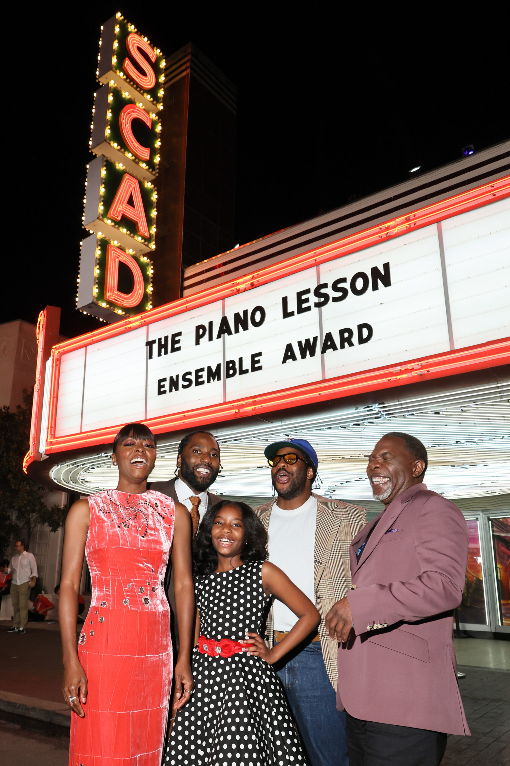 a group of people stand outside the SCAD Trustees Theater where a marquee says The Piano Lesson, Ensemble Award