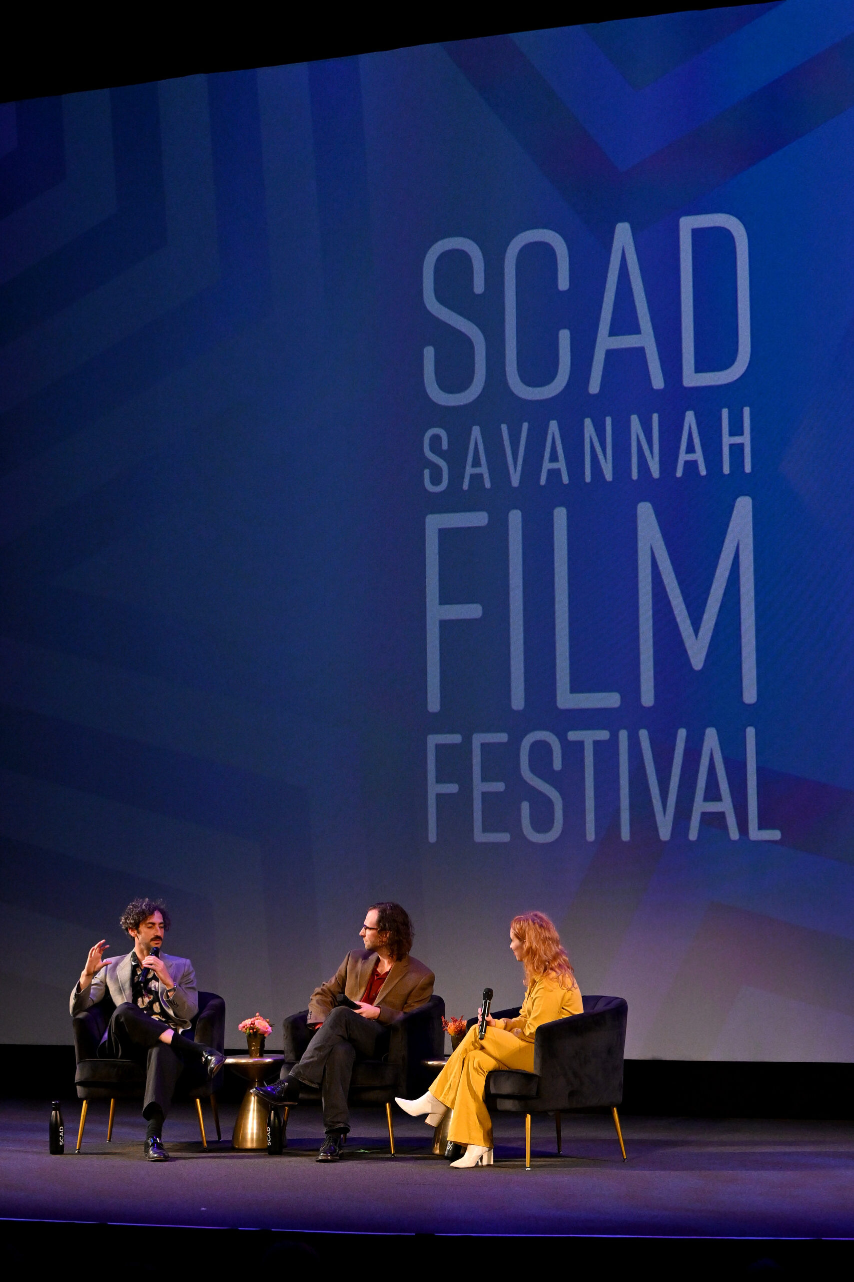 two men and a woman on stage at the Lucas Theater