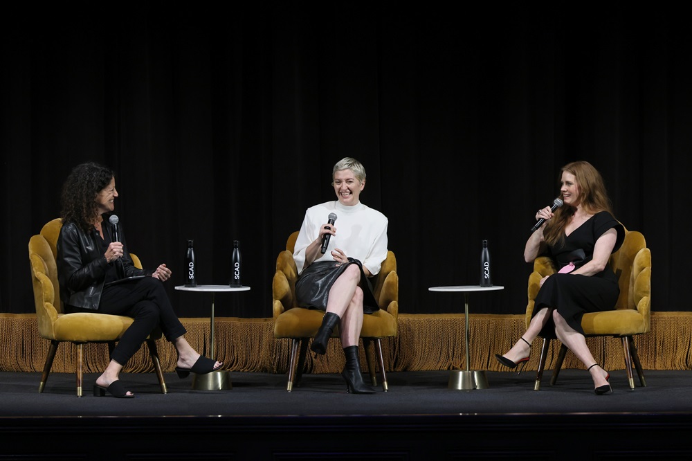 three women in chairs on stage