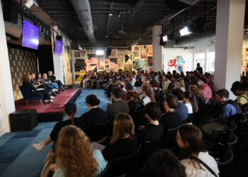 a group of people in a gallery with people on stage