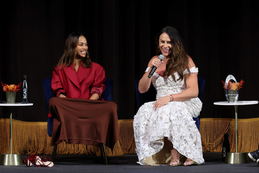 one woman in a red dress on stage and one woman in a white dress on stage