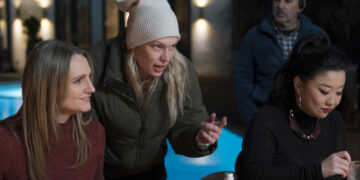 a woman directing two actors on set by a pool