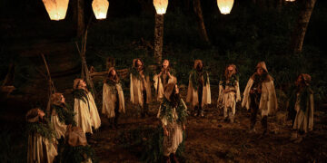 a group of people in head dresses and capes stand in a circle