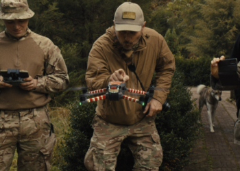 three men in army fatigues working a drone