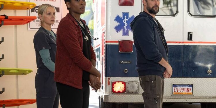 three people stand outside of an ambulance