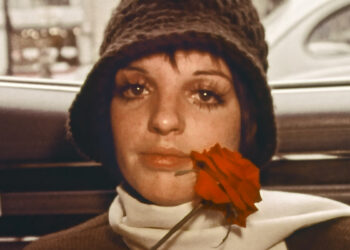 liza minnelli sitting in the backseat of a car holding a rose