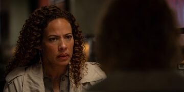 a woman looks at the back of the head of another woman across a diner booth