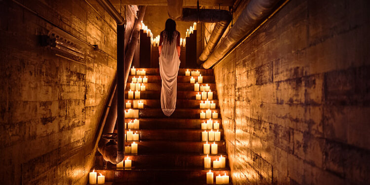 a woman walks up a stairway filled with candles