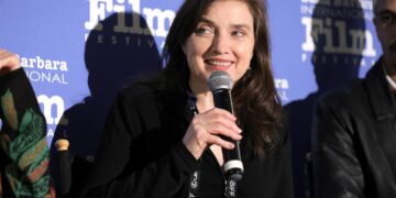 a woman with a microphone speaks at the santa barbara film festival