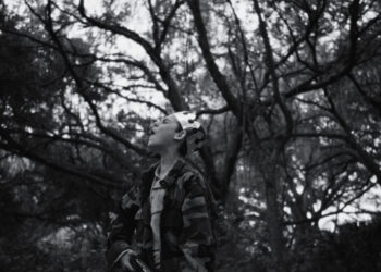 a boy wearing a crown screams in a forest