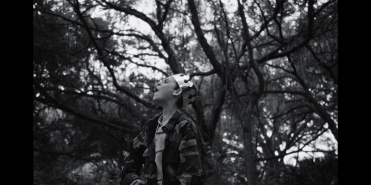a boy wearing a crown screams in a forest