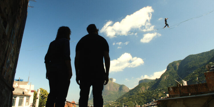 two men watch a man on a slackline