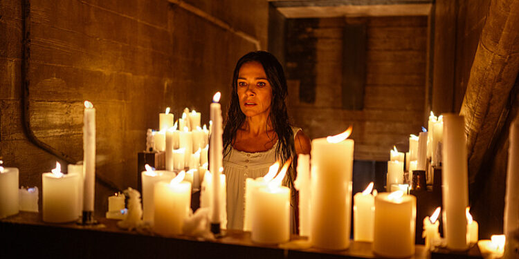 a woman stands in front of an altar of candles