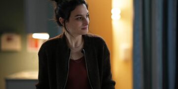 a woman with her hair up in a bun standing in a hospital room