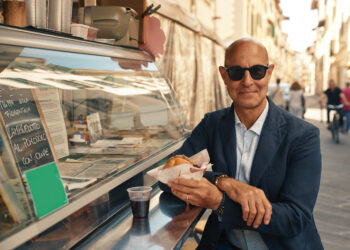 stanley tucci stands by a food stand in italy