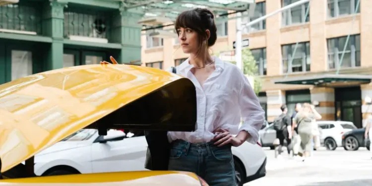 Dakota Johnson closes a cab trunk in Materialists