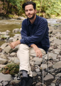 Composer-turned-director Matthew Dougherty sitting in a chair by rocks