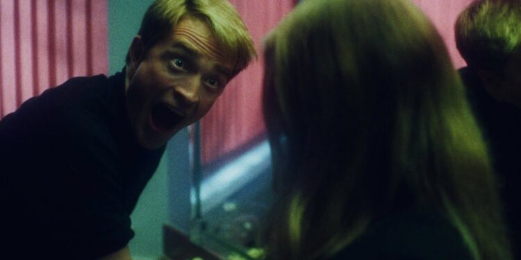 Primetime film still featuring Robert Pattinson making a face to someone in the bathroom